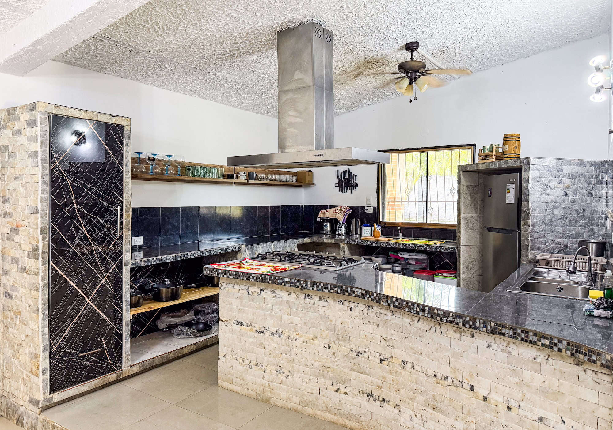 Moderní kuchyně s černými a kamennými prvky v Planet Patanemo.