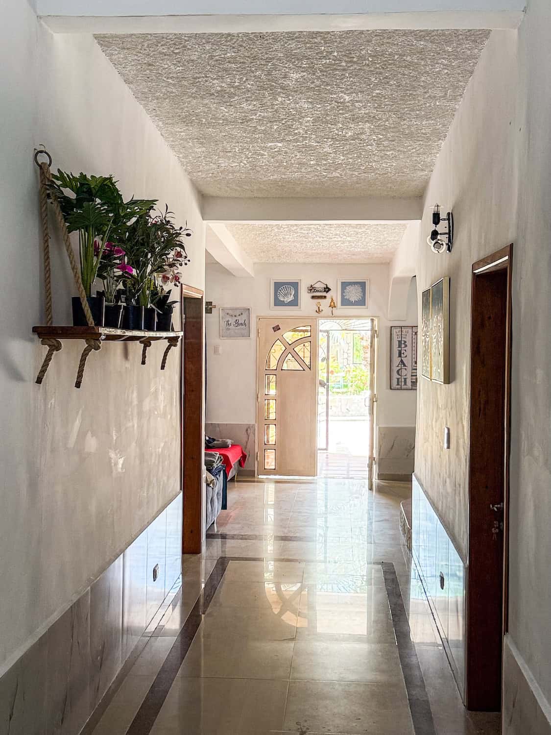 Interiérový pohled na vstupní halu s dekorativními prvky a květinami na levé straně.