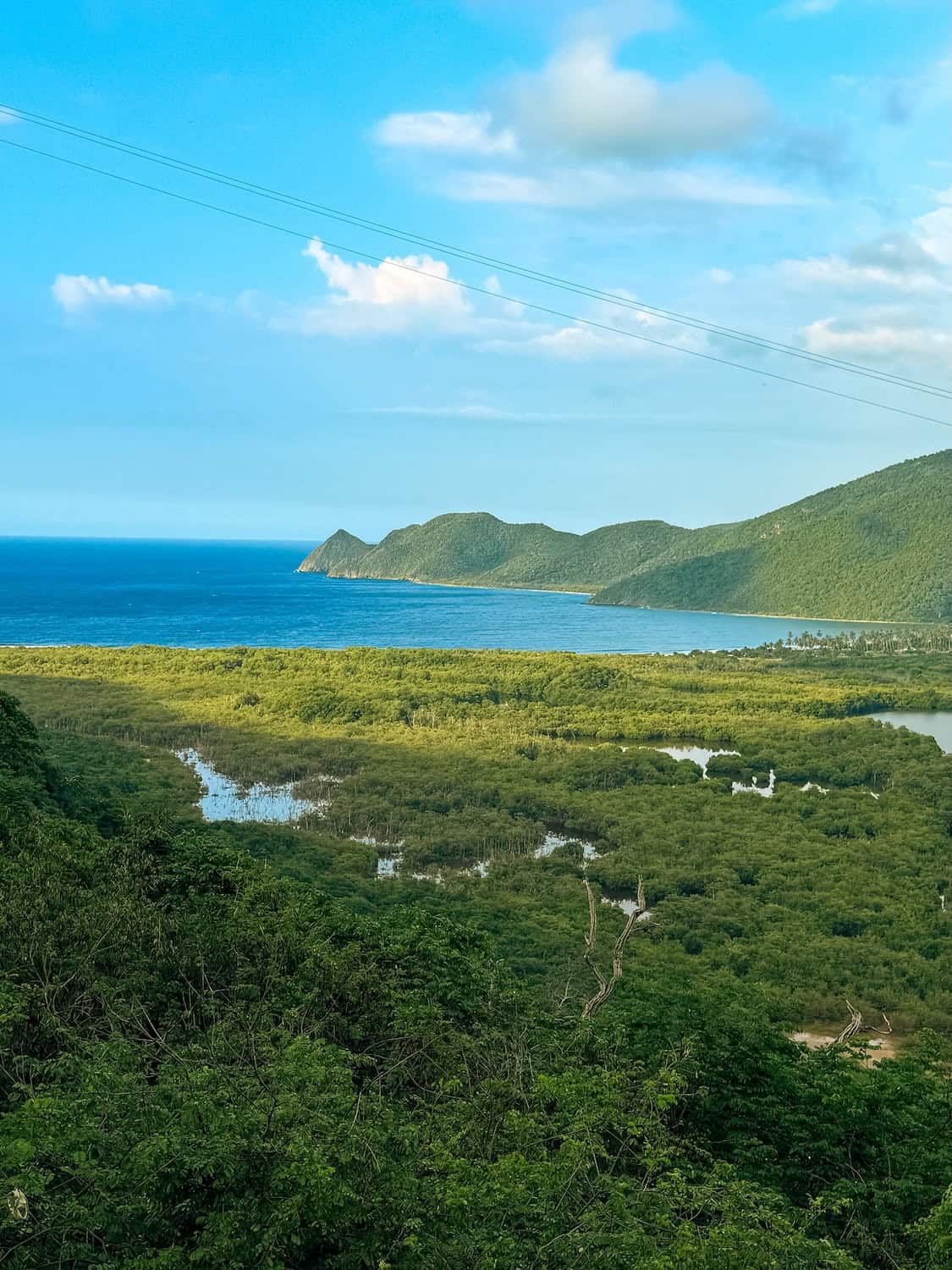 Přírodní scenérie s výhledem na oceán a zelené kopce v Planet Patanemo, Venezuela.