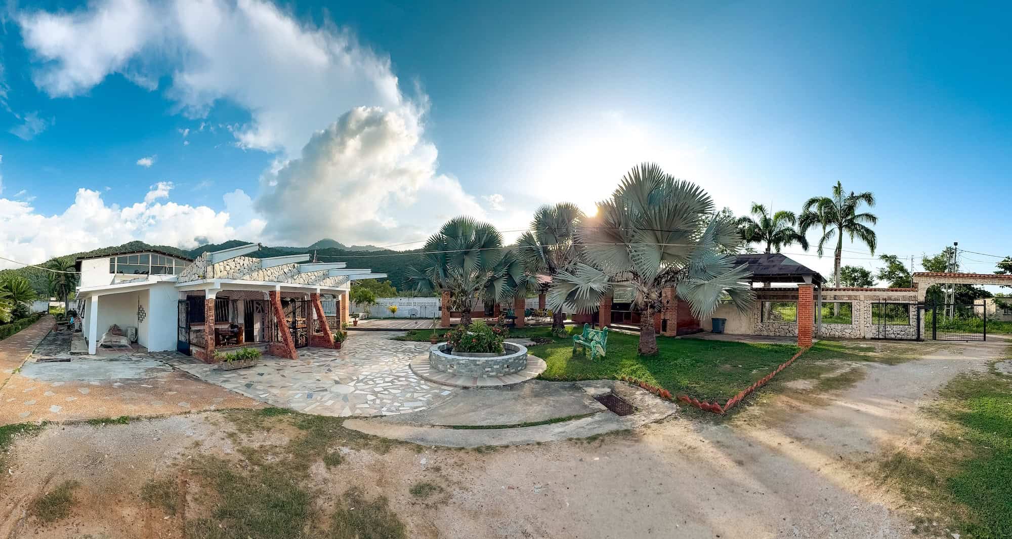 Exteriér resortu Planet Patanemo s palmami a bazénem za slunečného dne.