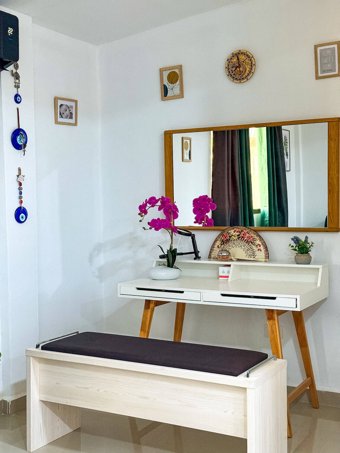 Interiér s květinovou dekorací, fialové orchideje na bílé konzoli, doplněné o dekorativní prvky a zrcadlo, vytvářejí příjemnou a elegantní atmosféru.