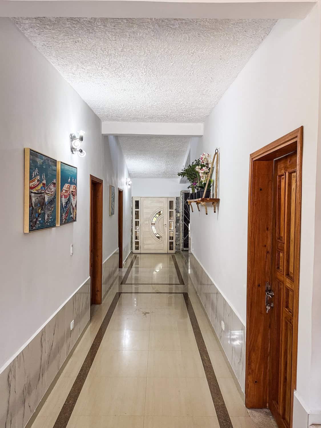 Vnitřní chodba hotelu Planet Patanemo s obrazy na stěnách a květinovou výzdobou.