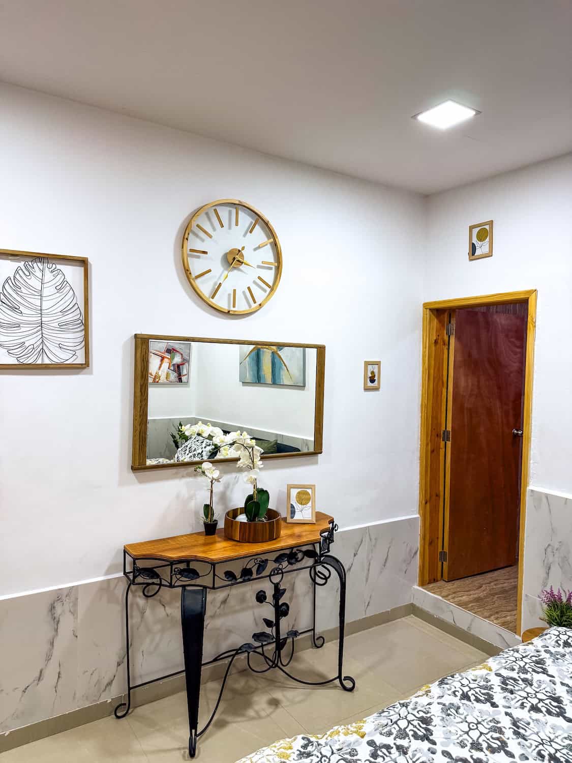 Interiér pokoje s nástěnnými hodinami a zrcadlem.