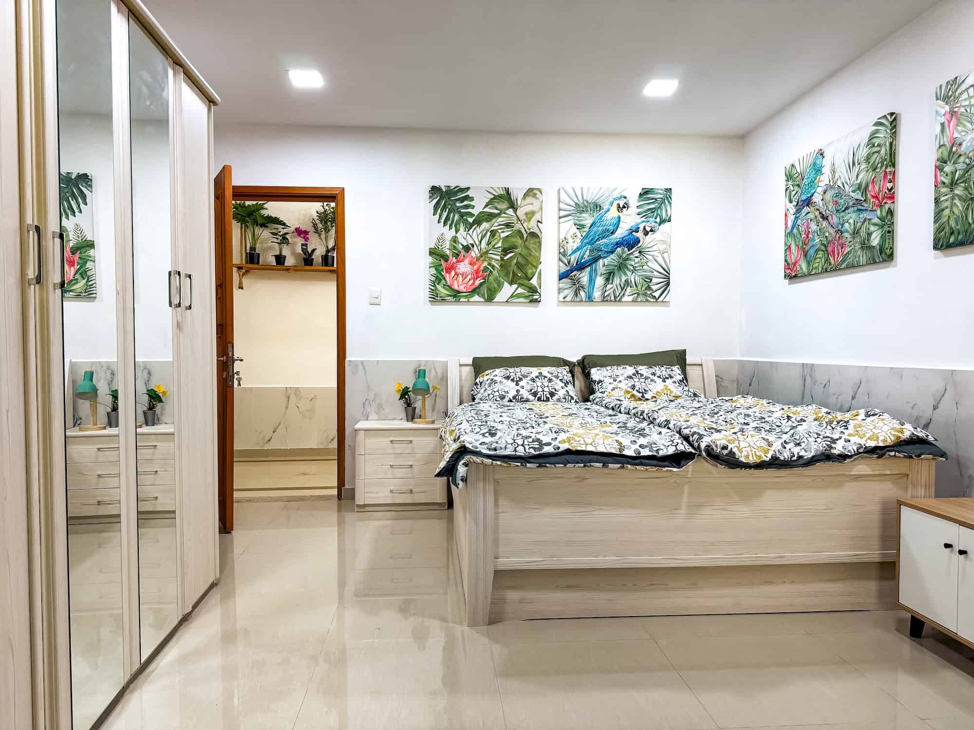 Moderní pokoj s tropickým motivem a uměleckými plátny na stěnách.