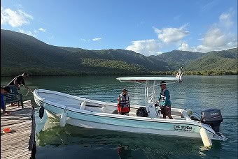 Plovoucí loď na jezeře Patanemo s výhledem na hory a modrou oblohu.