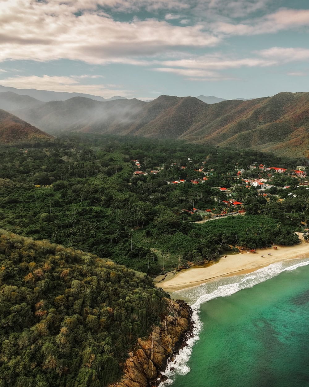 Pohled na pláž Patanemo s tyrkysovou vodou a okolní zelenou krajinou, ideální místo pro odpočinek